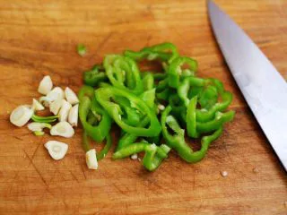 家常辣炒土豆丝,把蒜切成薄片,青椒切成丝。