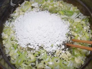 河南小吃——蒸素焖子,粉条煮10分钟即可关火。把葱、蒜和淀粉一块放进去,立即搅拌使葱、蒜、淀粉和粉条均匀混合。