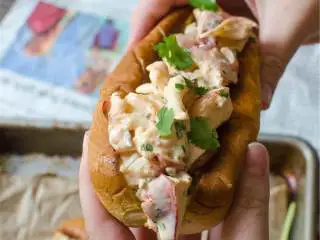 越南风味龙虾卷,将铸铁锅开中火，将融化黄油 抹到马铃薯面包 ，在锅里煮面包的两面，在面包上堆积龙虾沙拉，用多余的香菜和是拉差酱装饰.