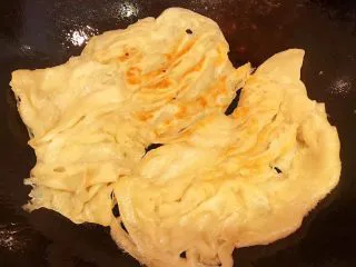 手抓饼开心早餐,锅中倒入少许油放入手抓饼中小火煎