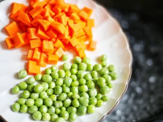 下饭神器小炒藕丁,中烧开水，放入青豆和胡萝卜。