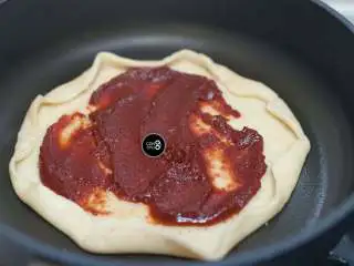 没有烤箱照样做出香浓芝士风味薄底披萨,锅底抹一层油,放入饼皮。抹上厚厚的番茄酱。