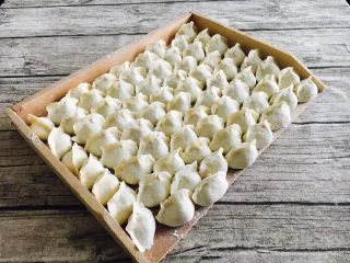 家乡风味饺子 三鲜馅饺子,把包好的饺子整齐的码放在饺子板上。 饺子板上要提前均匀地撒些面粉，避免饺子和饺子板粘连。