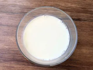 黑凉粉水果捞,把250毫升纯牛奶倒入碗里,加入适量白糖,用筷子把白糖搅拌至完全融化。