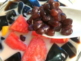 黑凉粉水果捞,加入黑凉粉,再加入芒果和西瓜,再放上蜜红豆,加入几块冰块即可。