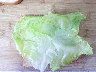 （创意菜）老干妈风味咸鸭蛋酒肠三明治,吐司上放一层生菜叶