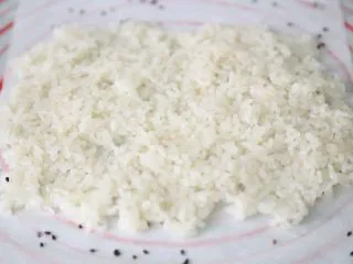 武汉小吃 糯米包油条,准备一碗凉白开,用勺子沾凉白开后,舀糯米,平铺在撒满黑芝麻的油纸上。 沾了凉白开的勺子,能够有效的防止粘连。