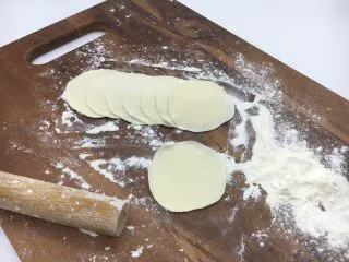 家乡风味饺子 三鲜馅饺子,把小圆剂子压平，擀成饺子皮，擀饺子要中间厚，周边薄。