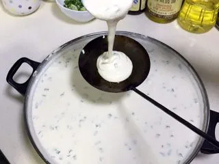 福建小吃—油饼,待油温加热超过180度时,从锅内取出油饼勺,往油饼勺内倒入一勺豆米浆。