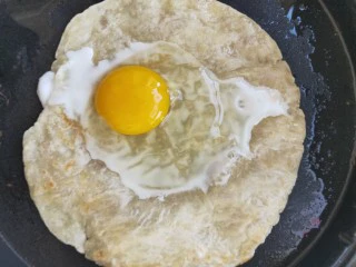 街头手抓饼的吃法----懒人必备早餐,打入一个鸡蛋在手抓饼饼上,关掉电饼铛下档,盖上盖子焖30秒。