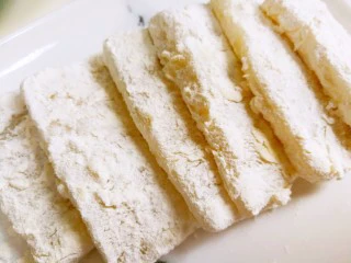 江南名小吃～炸年糕,把年糕片放在面粉里面裹一下，让四周裹满面粉