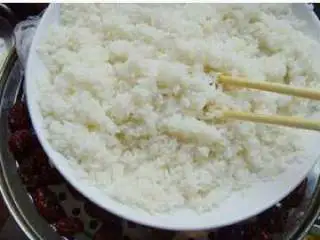 北京小吃:切糕,蒸制10分钟左右开盖,倒入开水,边倒开水边搅拌,使糯米充分吸收水分;带糯米完全被搅拌成浆糊状,盖上盖子继续蒸制15分钟左右。