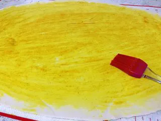 姜黄花卷，饮料做,在擀好的面饼上面，拿刷子刷上刚才调好的姜黄油，刷得均匀一致。