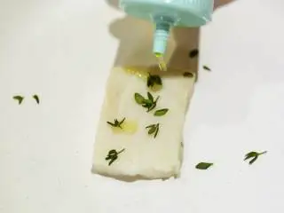 南法风味香煎银鳕鱼,在银鳕鱼 鱼带皮的一面划几道浅痕,撒上百里香 橄榄油 腌制。