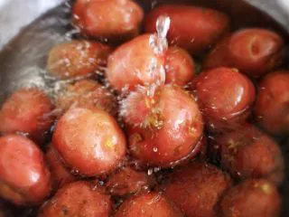 烧烤风味的香煎孜然小土豆,首先我们先把红皮小土豆来清洗一下，取一个盆子，把红皮小土豆放入盆子里用自来水先冲洗一下后，再用清水泡5分钟左右后，再用清水冲洗干净就可以了；