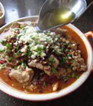 传统水煮牛肉,锅中再次烧热油，取适量浇在蒜末、青蒜苗和麻辣酥上，一定要听到“滋滋啦啦”的声音