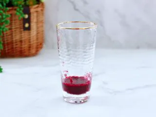 蔓越莓桑葚气泡水,取一个自己喜欢的杯子,把榨好的蔓越莓桑葚汁倒入杯底。