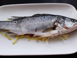 鲜美无比的粤式清蒸鲈鱼,把冲洗干净的鲈鱼铺到盘子上面。