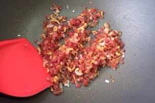 中式传统小吃——腊味萝卜糕,锅内油热后,先将虾米炒出香味,再混合洋葱和腊肠炒至腊肠出油