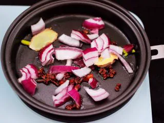 番茄牛肉炖土豆,煎锅里倒入花生油烧热后，先小火慢慢炸香花椒和八角，再爆香洋葱。