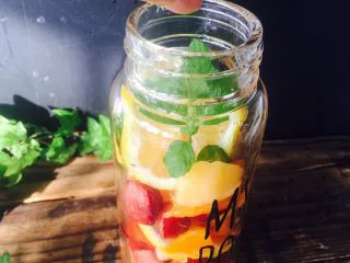 美丽的水果饮品,把薄荷叶放入瓶子