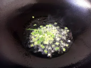 天津特色小吃 蔬菜烩饼,热锅凉油放入小香葱葱花,将葱花煸出香味。