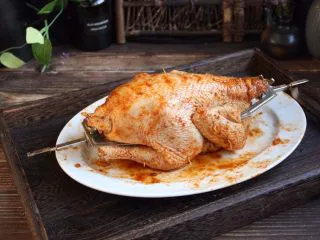 百变水果 新奥尔良风味雪梨烤鸡,将美的烤箱配置的旋转叉从三黄鸡的内脏穿过去，用锁扣紧紧锁住。