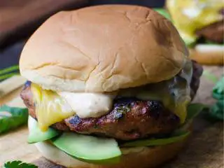 越南风味牛油果火鸡堡,将切片的牛油果 放在底部汉堡包的上面，再放上肉饼，加一汤匙是拉差蒜泥蛋黄酱 ，如果需要的话还可额外加入些香菜叶，上菜并享用吧！
