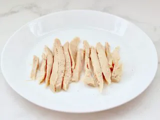 风味酸黄瓜鸡肉热压三明治,把加热好的鸡胸肉，用刀切成粗条。