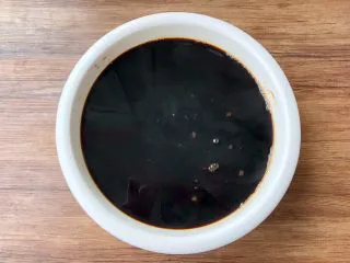 黑凉粉水果捞,把煮好的黑凉粉糊倒入大碗或者模具里,晾凉以后盖上保鲜膜,放入冰箱冷藏2个小时。