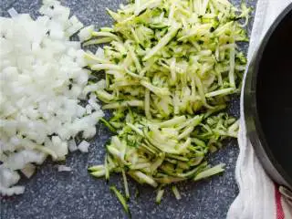 地中海风味火鸡肉丸,烤箱预热至200摄氏度。准备两个烤盘，用烘焙纸把烤盘包起来，撒上蔬菜碎。中号洋葱 细细切碎，中号西葫芦 擦碎，酸豆和番茄干 沥干水分，切碎大蒜瓣 ，放在一旁备用。