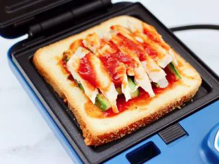 风味酸黄瓜鸡肉热压三明治,三明治提前预热后，放入三明治。