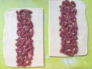 意式红烩牛柳酥,用筷子夹上腌制好的牛柳,均分2份,平铺在面片中间