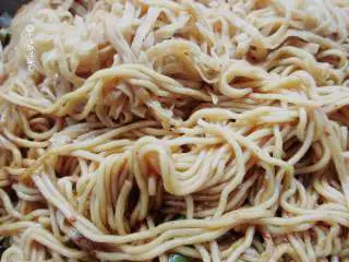 五花肉豆角焖面,中途可以用筷子扒开锅底的小口，看一下菜汁是否收干。如果汤汁收干而面不太熟，就兑加少量热水至汁差不多干了,面也熟了的程度。 切记：中途不要翻动面条。在面条熟之前翻动就会使面条糊化成一坨了。焖好后，再用筷子把面条扒拉散开，使面与菜混合好