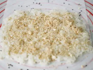 武汉小吃 糯米包油条,将打成粉的花生粉均匀的洒在铺好的糯米饭上。