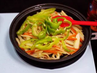 家常辣炒土豆丝,大火继续翻炒均匀后,把切丝的青椒放入锅中。