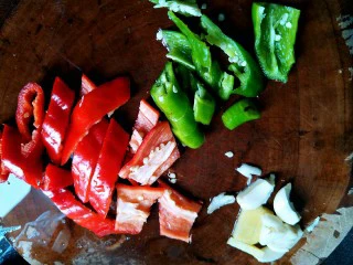 让你停不下来的爆炒花甲,青红椒洗干净，去头尾，切小块，蒜头拍扁去皮，姜块去皮切片。