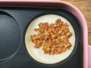 复刻街头美食~网厨第一个肉蛋堡,给有面糊的圆盘里,用筷子夹一些已经调好味的肉馅铺在面糊上。