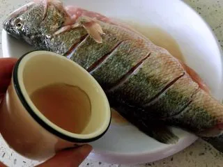 清蒸鲈鱼#年年有余#,料酒搓鱼身。