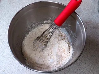 醇厚风味的咖啡百利甜费南雪,将混合过筛的粉类一起加入蛋白盆中，用手抽继续混合，至无干粉状态即可