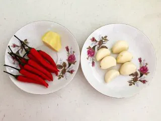 私房菜 密制酸辣鸡爪,把鲜姜削皮,蒜瓣和小米辣清洗干净