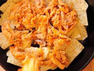 三种芝士布法罗风味鸡肉玉米脆饼,玉米片上再铺一半的鸡肉混合物。