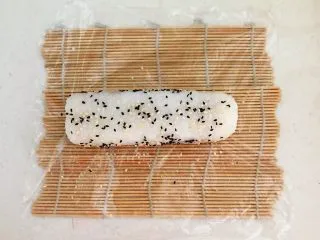 上班族的便当 风味独特的粢饭团,打开保鲜膜,在卷好的饭团上均匀的撒上一层黑白芝麻