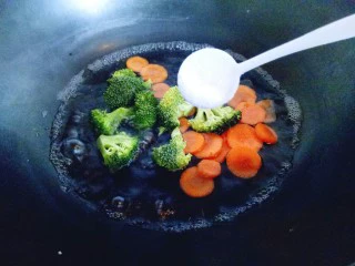 #东南亚风味的#椰汁咖喱虾,锅中加入水，大火烧开，把切好的胡萝卜和西兰花一起倒入锅中，加一勺赞，大火焯水1分钟即可，捞出立即过冷水。