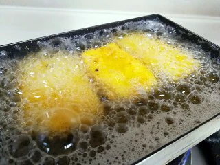 江南名小吃～炸年糕,转中小火，把年糕片放进锅里，炸至两面金黄色