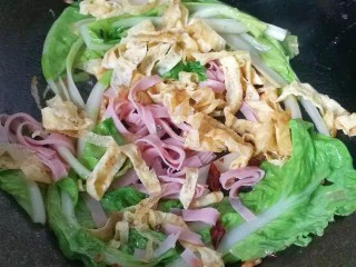 火腿鸡蛋炒面,再放入火腿丝和鸡蛋皮，加少许盐翻炒均匀；