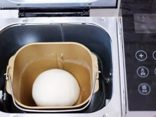 百吃不厌的韭菜盒子,和好的面团用手揉圆后放入面包桶里静置一会。