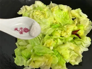 炝炒手撕包菜,快速翻炒均匀，让菜叶都沾上油汁后，加入适量的盐。