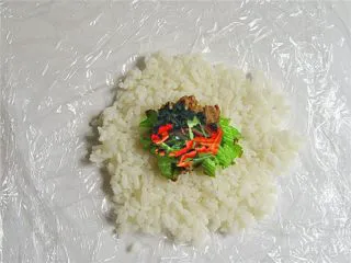 可爱的企鹅饭团,在双层保鲜膜上铺好米饭放上家常菜做馅儿,不要放得太多,饭团不容易团起来