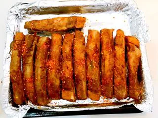 东北风味 密制香辣大肋排,把烤盘取出来,在排骨上面均匀的撒一层辣椒粉